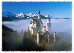 an image of a castle in the middle of the woods with mountains and clouds behind it