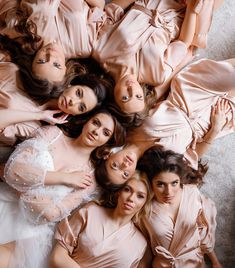 four women in pink dresses are laying on the floor and one is wearing a white dress