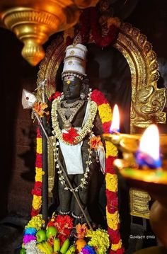 the statue is decorated with flowers and other decorations in front of a lit candle holder