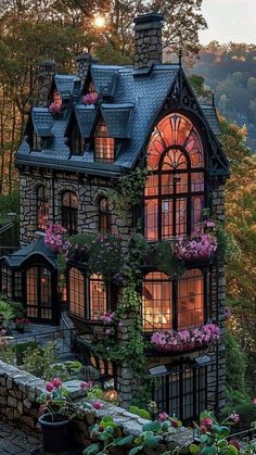 a house that is surrounded by flowers and trees