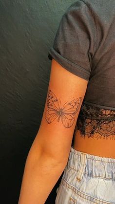 a woman with a butterfly tattoo on her left arm and lower back half - sleeve