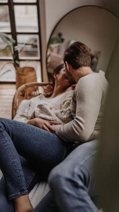 a man and woman are sitting on a couch with their arms around each other as they cuddle