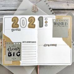 an open planner book on top of a table with papers and pencils next to it