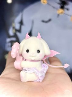 a small white teddy bear wearing a pink dress and holding an umbrella in it's hand