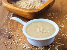 a white bowl filled with oatmeal next to a wooden spoon on top of a table