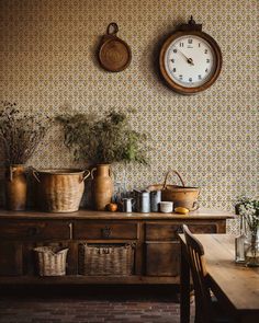 an old fashioned kitchen with pots and pans on the counter next to a clock