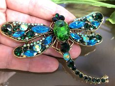 a green dragon brooch sitting on top of a person's hand