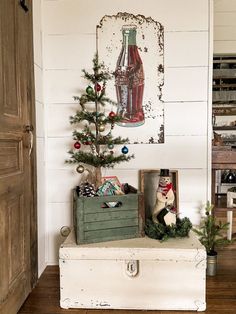 a small christmas tree sitting on top of a white trunk in front of a wall