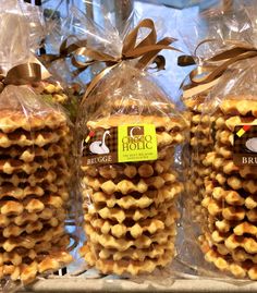 several bags of cookies wrapped in plastic and tied with brown ribbon, sitting on a shelf