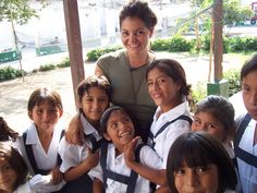 a woman posing for a photo with school children