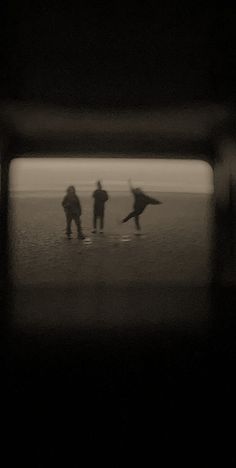 three people are walking in the water with their surfboards