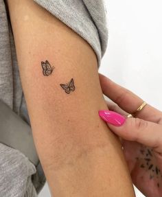 a woman's arm with two small butterflies on the back of her left arm