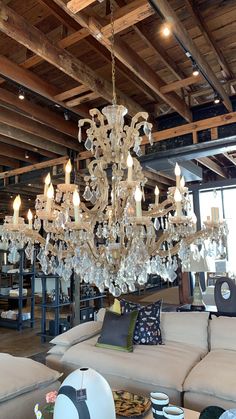 a large chandelier hanging from the ceiling in a room with couches and tables