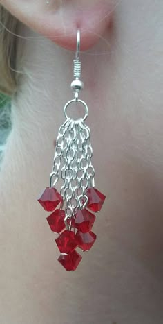 a close up of a person's ear with red beads hanging from the side