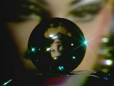 a close up of a woman's face with green lights on her eyes and an object in the foreground