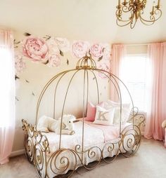 a pink and white bedroom with floral wallpaper, gold metal bed frame and chandelier