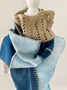 a white mannequin head wearing blue jeans and a crocheted sweater