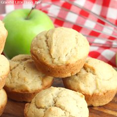 a pile of muffins sitting on top of a wooden table next to an apple