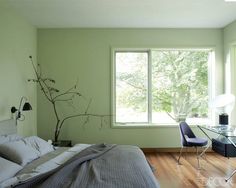 a bedroom with a bed, desk and chair next to a large window in the room