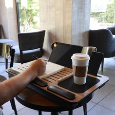 a person's hand writing on a notepad next to a cup of coffee