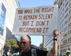 a man holding a sign that says you have the right to remain silent but i don't recommend it