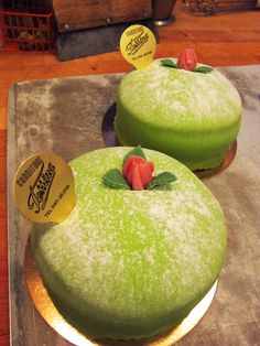 two green cakes sitting on top of a wooden table