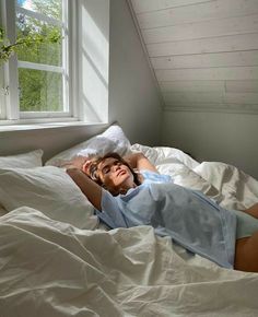 a woman laying in bed with white sheets