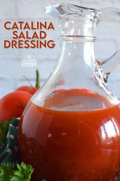 a glass jug filled with tomato juice and garnished with parsley on the side