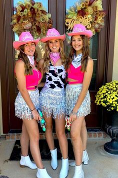 three girls in cowboy hats and fringe skirts posing for the camera with one girl wearing a cowgirl costume