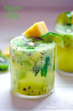 two glasses filled with pineapple mojito on top of a table