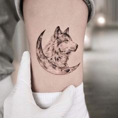 a woman's thigh with a wolf on it and the moon in the background