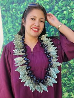 a woman wearing a purple dress and a necklace with leaves on the front, smiling