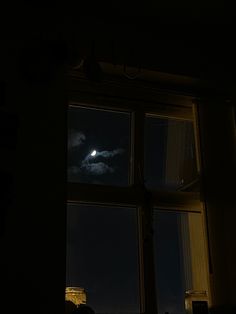 the moon is shining brightly in the dark night sky behind a window with no curtains