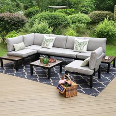 a couch and coffee table on a deck in the middle of a yard with trees