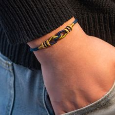 a close up of a person wearing a bracelet with an intertwined knot on it