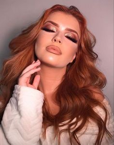 a woman with long red hair and gold eyeshadow is posing for the camera