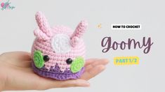 a hand holding a small crocheted toy with the words goony on it