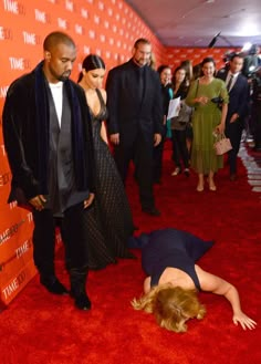 a woman laying on the ground next to a man in a black suit and tie