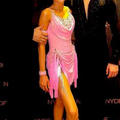 two people standing next to each other in front of a red carpet and black background