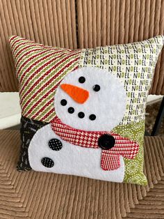 a snowman pillow sitting on top of a couch next to a brown sofa cushion