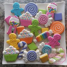 a white plate topped with lots of colorful cookies and candies on top of a table