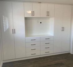 an empty room with white cupboards and drawers on the wall next to a door