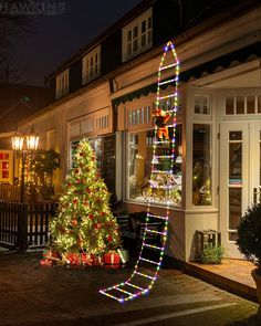 a decorated christmas tree in front of a store at night with lights on the windows