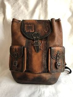 The lined interior is wide open, with one small zippered pocket along the side that would be against your back. Vintage Leather Backpack For School, Vintage Backpack For Trips, Vintage Rectangular Leather Backpack, Vintage Standard Backpack For Trips, Vintage Satchel Backpack For Trip, Vintage Leather Backpack For Trips, Vintage Brown Backpack For Trip, Brown Vintage Backpack For Trips, Embossed Bag