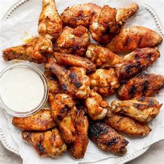 grilled chicken wings with ranch dressing on a white platter, ready to be eaten