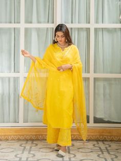 Set of 3 consists of kurta, palazzo and dupatta. Noor, bringing the magic of festivities straight to your closet in shades of pastels. Delicately adorned with mirror & gota detailing Kurta: A minimal straight fit cheerful yellow kurti with gota &mirror detailing on the neckline, sleeves & hemline. Dupatta: An elegant sheer kota doria dupatta, complete with mirror work & chevron pattern gota detailing adorned with handmade gota tassels. Pants: Straight fit cotton pants enhanced wi Yellow Suit Indian, Palazzo Kurta, Yellow Kurti, Yellow Mirrors, Haldi Outfit, Kurta Patterns, Yellow Suit, Fancy Kurti, Kurtis With Pants