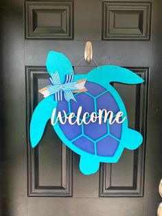 a welcome sign hanging on the front door of a house with a sea turtle painted on it