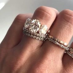 a woman's hand holding two rings with diamonds on top of each one and the other