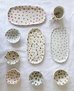 six different types of dishes and cups on a white tablecloth with polka dot designs