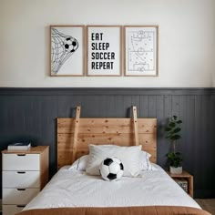 a soccer ball sitting on top of a bed next to two framed pictures above it